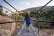 © zhukovvvlad - hiking with children. rear view. a boy with a backpack crosses the canyon through a rope bridge. traveling with children.