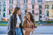 © Martí Rosselló - Two Smiling Women Walking Together in Urban Street. Happy women walking and talking outdoors in city, enjoying a casual conversation on a winter day.