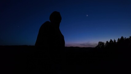 Wall Mural - silhouette of a man observing milky way stars, moon and planets from a countryside location.