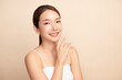© kitthanes  - A beautiful young Asian woman with clean, fresh skin against a beige background. Skincare, facial treatment, cosmetology, beauty, and spa. An elegant portrait of an Asian woman.