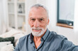 © InsideCreativeHouse - Happy senior man with gray hair smiling at home. Old man relaxing on sofa and looking at camera. Elderly man enjoying retirement. Healthy medicine banking insurance investments finance concept