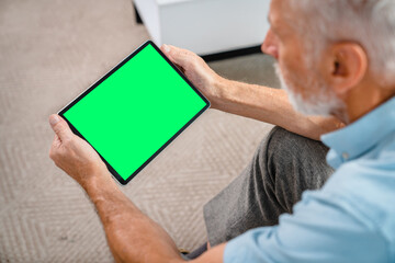 handsome senior old man using digital tablet with mock up blank screen while sitting relaxing restin