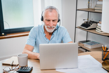 Happy senior Caucasian man in wearing headphones, helping as call center consult assistant. Smiling mature 60s years old businessman holding video call with clients partners. Copy space