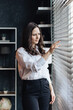 © Irina Brinza - Businesswoman looking through window blinds in modern office. Vertical photo