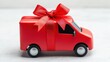 © Kittichet - A vibrant red toy delivery van decorated with a large red ribbon bow presented as a delightful gift for children or festive occasions, perfect for playtime