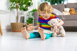 © yanadjan - Child reading a book at home with a teddy bear at home. Selective focus.
