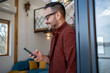 © Migma_Agency - Smiling man using smartphone at home reading good news