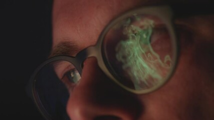 Flames reflect in a man's glasses as he calmly watches the fire, his face lit by flickering light in slow motion.