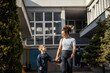 © Dusan Petkovic - Mother and her kindergartener holding hands in front of school building while smiling at each other.