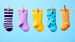 © LAILY - Colorful baby socks hanging on a clothesline against a light blue background