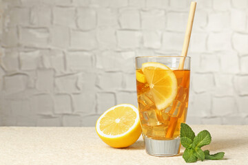 Wall Mural - refreshing iced tea with drinking straw, mint and slices of lemon on light textured table against gr