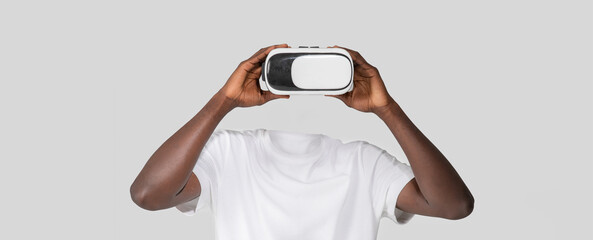 Poster - A person engages with virtual reality technology using a headset that covers their eyes, creating an illusion of a headless figure. The background is simple and neutral.