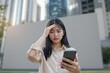 © peshkova - Concerned young woman looking at smartphone outdoors.