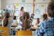 © peshkova - Students raising hands in classroom during lesson.