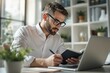 © peshkova - Focused businessman working at desk with laptop and notebook.