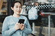 © zhouyilu - Young Woman Engaged with Smartphone in Modern Caf? Setting
