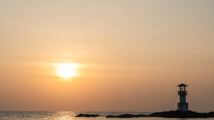 Wall Mural - light house on sea beach with sunset sky clouds in the evening, beacon light tower for guiding trave