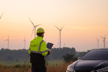 Poster - Engineers male flying drone surveying and checking wind turbines from the high angle view of the field during beautiful sunset. using drone technology for work.