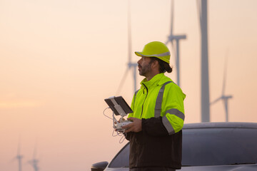 Aufkleber - Engineers male flying drone surveying and checking wind turbines from the high angle view of the field during beautiful sunset. using drone technology for work.