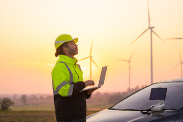 Aufkleber - Engineer working on laptop in front of wind turbines for checking wind turbines of the field during beautiful sunset. Alternative energy concept.