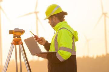 Poster - Engineer working on laptop in front of wind turbines for checking wind turbines of the field during beautiful sunset. Alternative energy concept.