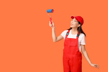 Wall Mural - female asian painter with roller on orange background