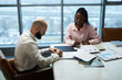 © DragonImages - High angle view of businessman signing contract while having meeting with colleague in boardroom
