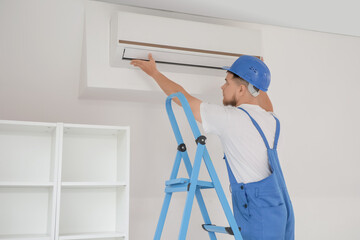 Wall Mural - male contractor on stepladder installing air conditioner in room