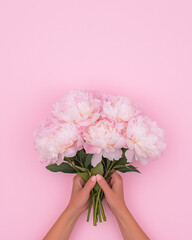 Aufkleber - A soft-focus image of a motherâ€™s hands holding a bouquet of peonies, laid over a pink background