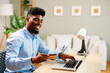 © djile - Happy young professional is making online payment holding credit card and using laptop while working from home
