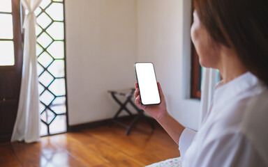 Wall Mural - mockup image of a woman holding mobile phone with blank desktop screen at home