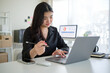 © wattana - Focused young businesswoman holding pen working with laptop in modern office.