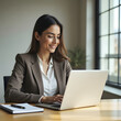 © macbon - Mujer de negocios hispana analizando su trabajo en su laptop.