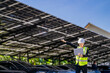© ultramansk - Engineer in safety vest and helmet pointing towards a solar powered carport, illustrating eco-friendly innovation in parking infrastructure. Solar panels provide shade and sustainable energy.