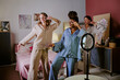 © AnnaStills - Wide shot three besties in pajamas dancing while recording funny video to post it on social media