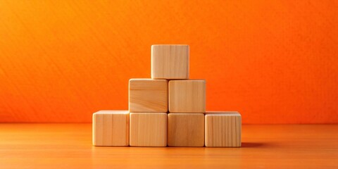 Aufkleber - Wooden blocks arranged in a pyramid shape against a vibrant orange background.