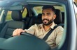 © Maryna - Handsome latin man drives car, wearing seatbelt, smiling. Happy driver inside automobile. Safe driving concept, road trip, traveling. Businessman taxi driver with vehicle, new car purchase, auto