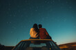 © wolfhound911 - A young Hispanic couple sitting on the hood of a car, watching the stars together in the countryside.