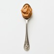 © EddieSnapix - A shiny spoon holds a generous dollop of creamy peanut butter against a plain background, showcasing its rich texture and inviting appearance for various culinary uses