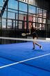 © Wavebreak Media - Woman playing padel tennis indoors, hitting ball with focused expression, copy space
