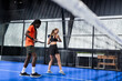 © Wavebreak Media - African American man and woman playing padel tennis on indoor court, enjoying game