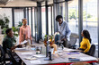 © Wavebreak Media - In modern office, diverse team discussing ideas and sharing documents collaboratively