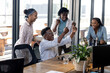 © Wavebreak Media - Diverse team celebrating success at office, cheering and smiling around desk