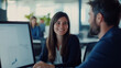 © Sergio IQstock - Young businesswoman and businessman collaborating at a computer in a modern open-plan office, smiling and discussing a digital project team collaboration, business partners, workin