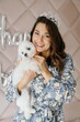© nazariykarkhut - Smiling woman wearing crown holding adorable white dog with colorful fur
