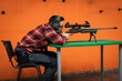 © Dmitri - A civil shooter aims a sniper rifle from a sitting position at a shooting range.