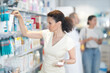 © JackF - Adult woman shopper in casual clothes chooses medicine at pharmacy