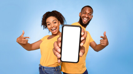 Wall Mural - use this new mobile app. joyful african american couple pointing at smartphone with empty white scre