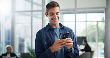 Fototapete - Typing, creative and business man with phone in office for networking, text message or brand specialist online. Mobile, startup and happy worker reading email, campaign and promotion on social media