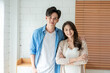 © Kawee - Portrait of Asian young couple standing in living room at home.